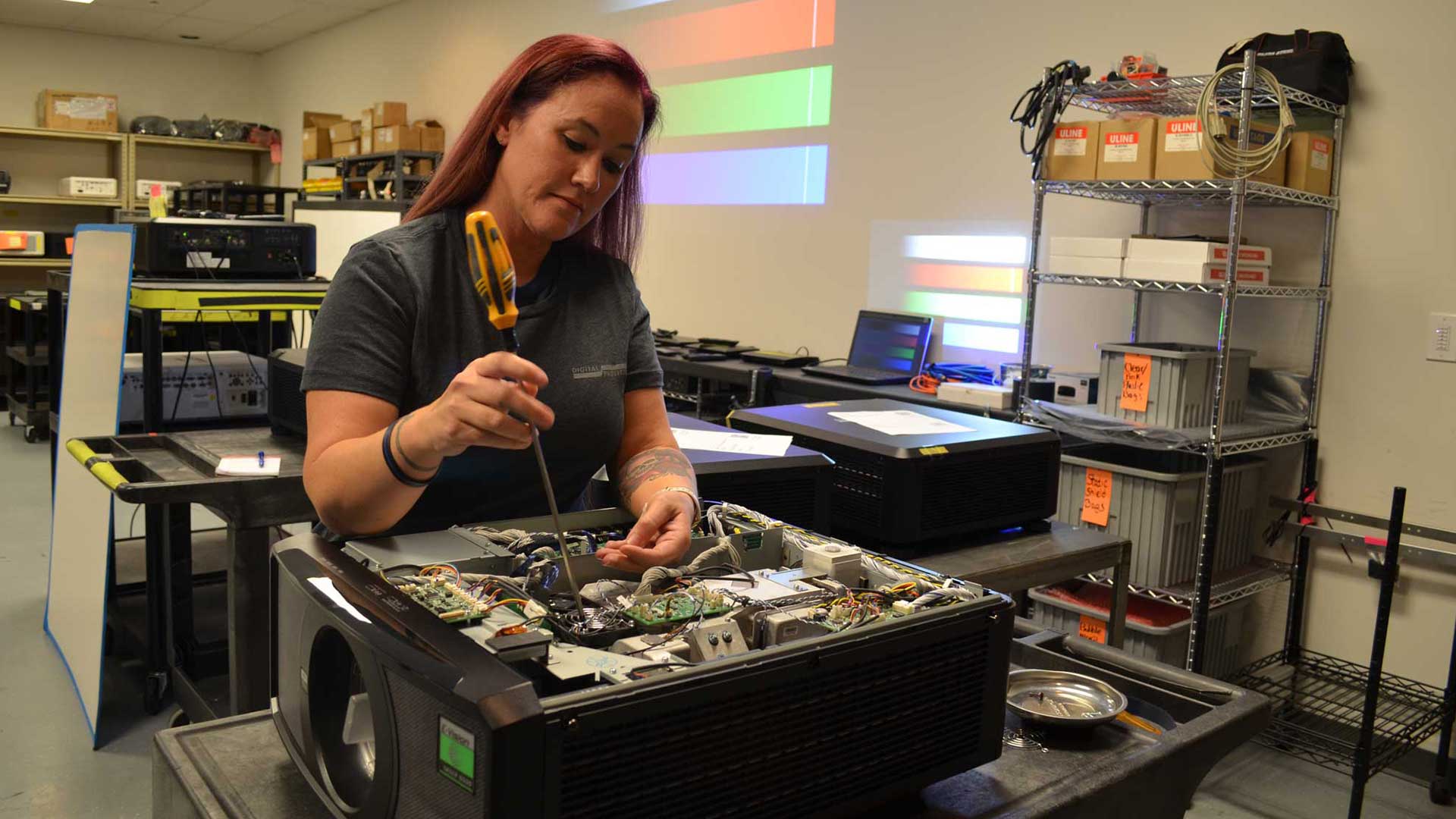 Digital Projection technician repairing a projector